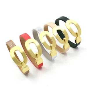 Dettaglio di bracciali in pelle con grandi fibbie ovali dorate in vari colori