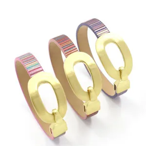 Dettaglio di tre bracciali in pelle a righe colorate con fibbie ovali in oro opaco