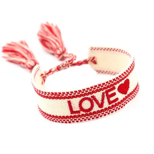 Detail of bohemian hand-woven bracelet with red LOVE embroidery and tassel accents