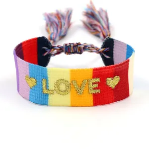 Close-up of rainbow woven bracelet with gold LOVE embroidery and colorful tassels