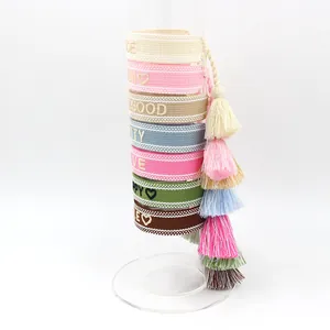 Colorful embroidered woven bracelets set with bohemian fringe tassels on a display stand