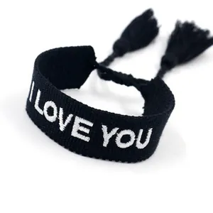 Detail of embroidered I LOVE YOU lettering on black woven friendship bracelet with tassels