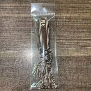 Dettaglio di un braccialetto dell'amicizia intrecciato marrone e bianco con ricamo LOVE