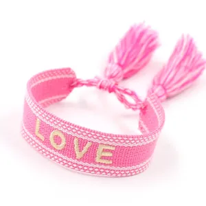 Pink woven friendship bracelet with LOVE embroidery and adjustable tassels on white background