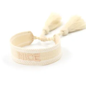 Close-up of beige woven friendship bracelet with NICE embroidery and soft tassels