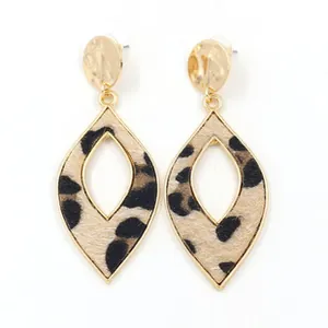 Detail of leaf-shaped gold alloy earrings with leopard print fabric inlay and round studs