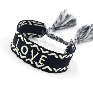 Detail of black and white woven bracelet with LOVE embroidery and fringe tassels
