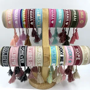 Detail of woven friendship bracelets with embroidered motivational text and tassels