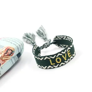 Ethnic woven friendship bracelet in dark green with golden LOVE embroidery and tassel detail
