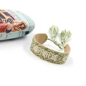 Detail of woven friendship bracelet with HAPPINESS embroidery and green tassel