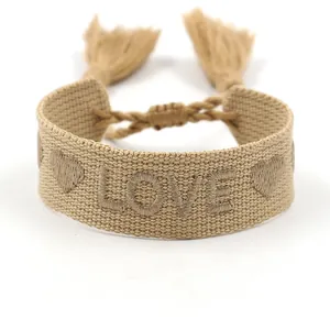 Détail du bracelet d'amitié tissé kaki avec broderie LOVE et pompons de style bohème
