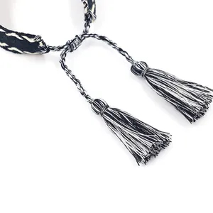 Detailed view of black and white woven friendship bracelet with tassels and sliding knot