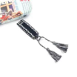 Macro detail of hand-woven black and white friendship bracelet with tassel and fringe