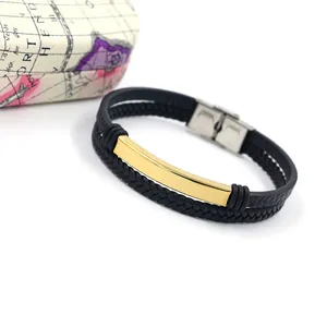 Detalle de pulsera de cuero negro de doble capa con placa de metal dorada pulida