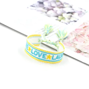 Detail eines gewebten Freundschaftsarmbands mit LOVE-Stickerei und bunten Quasten