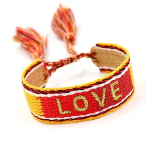 Close-up of bohemian friendship bracelet with red and yellow webbing and gold LOVE embroidery