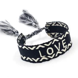 Close-up of woven friendship bracelet with LOVE embroidery and black tassels