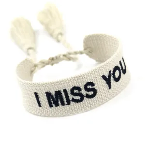 Detail of woven cotton bracelet with I MISS YOU embroidery and soft tassels