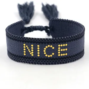 Macro detail of deep blue woven bracelet featuring golden NICE text and adjustable tassels