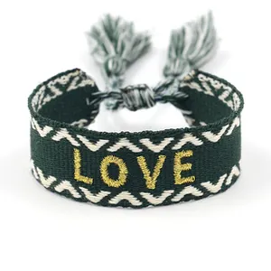 Detailed embroidery of gold LOVE text on green woven bracelet with tassel ties