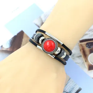 Macro detail of multi-layer black leather bracelet with red stone inlay on a wrist