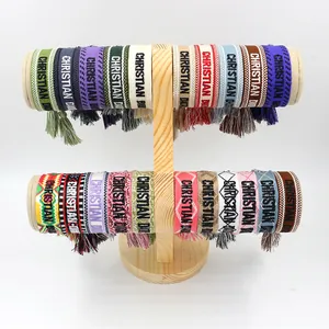 Detalle de pulseras tejidas bordadas de colores con borlas en un soporte de madera