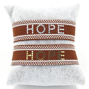 Bracelets en ruban marron avec lettrage HOPE métallique sur un coussin en peluche