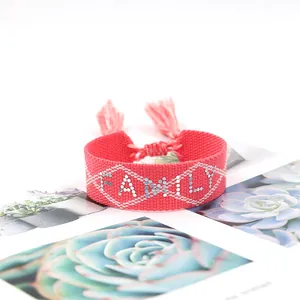 Close-up of pink woven bracelet featuring beaded FAMILY text and decorative tassels