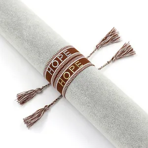 Détail macro du bracelet tressé avec inscription HOPE et pompons décoratifs élégants