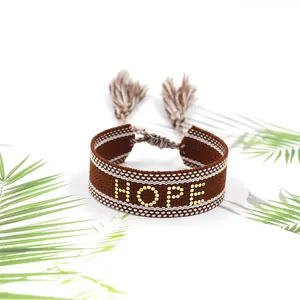 Vue détaillée du bracelet tissé marron avec clous dorés HOPE et pompons à franges