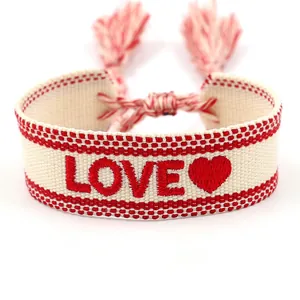 Pulsera tejida bordada en crema y rojo con motivo LOVE y detalles de borlas rojas