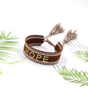 Détail d'un bracelet tissé marron avec lettrage HOPE et pompons de style ethnique