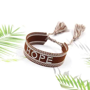 Détail du bracelet tissé marron Hope avec motifs à pois blancs et pompons à franges