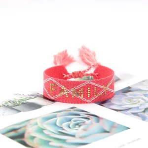 Detail of pink woven bracelet with golden FAMILY letter beads and tassel closure