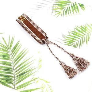 Détail d'un bracelet tissé boho avec texte HOPE jaune et accents de glands bruns