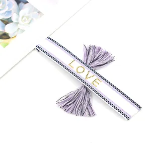 Lavender woven bracelet with LOVE lettering and tassel detail on white background