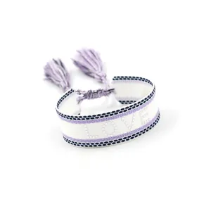 Close-up of purple and white woven LOVE bracelet with intricate embroidery and tassel details