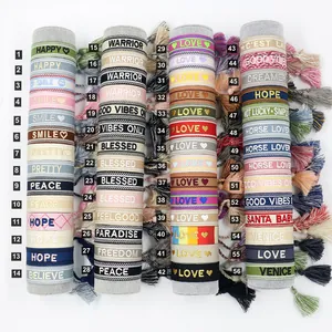 Detailed macro view of bohemian woven friendship bracelets with embroidered slogans and tassels