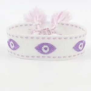 Detailweergave van geweven Evil Eye borduurwerk met lila kwastjes en fijne stiksels