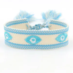 Detail van handgeweven vriendschapsarmband met evil eye patronen en blauwe kwastjes