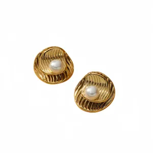 Eleganti orecchini a goccia in oro con texture a onde e perle bianche su sfondo bianco