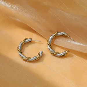 Dettaglio di orecchini a cerchio a C bicolore oro e argento in acciaio intrecciato