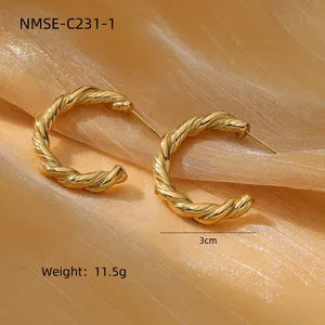 Detail of 3cm twisted golden C-shape stud earrings in polished stainless steel