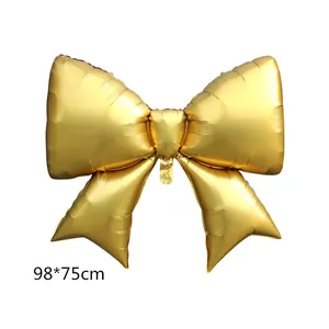 Detail of a large 98x75cm golden bow foil balloon with metallic finish for birthday parties