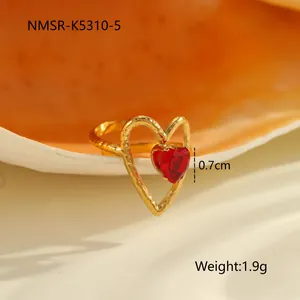 Détail d'une bague cœur plaquée or avec zircon rouge et texture métallique martelée