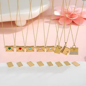 Detalle de colgantes de sobre dorados con gemas de corazón y placas grabables para joyas