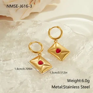 Détail de boucles d'oreilles enveloppe dorées avec zircon coeur rouge en acier
