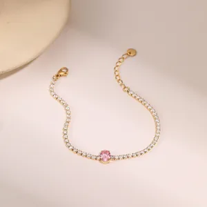 Detalle de una pulsera dorada con gema rosa ovalada y engaste de circonitas blancas