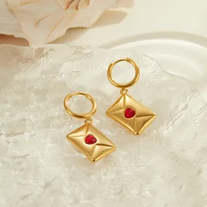 Vue détaillée de boucles d'oreilles enveloppe en or avec un zircon rouge en forme de cœur