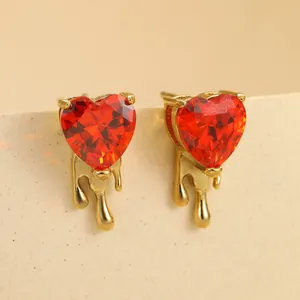Vue macro de boucles d'oreilles cœur en zircon rouge avec design goutte de métal doré